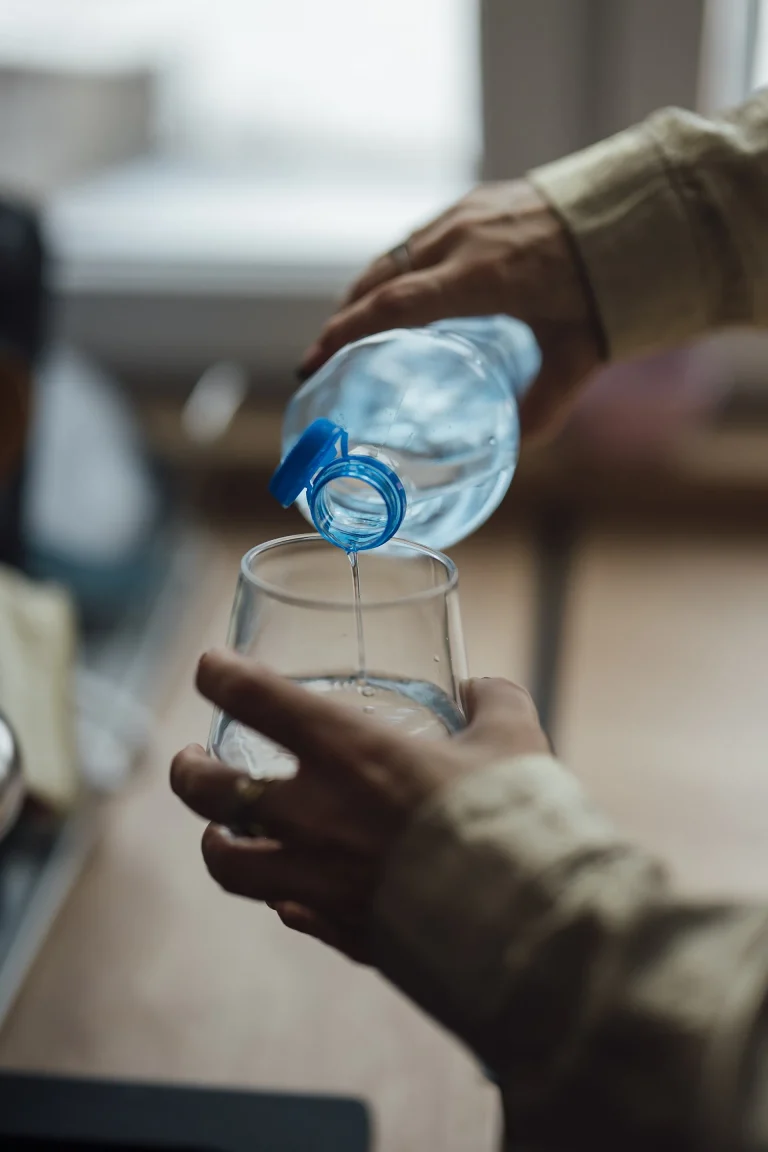 Why Shoppers Still Reach for Bottled Water They Say They Distrust Hands pouring water from a bottle into a drinking glass - Why Shoppers Still Reach for Bottled Water They Say They Distrust